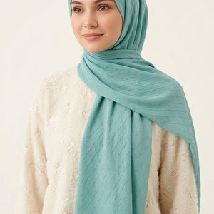 Turquoise quilted fabric with a brand logo in the center