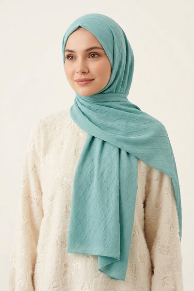 Turquoise quilted fabric with a brand logo in the center