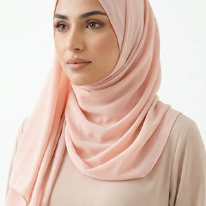Pink scarf draped over a white surface with a subtle pattern